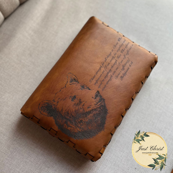 The backside of the bible cover is shown in the image. The Bible Cover is placed on a material background. A big bear and verse is engraved on the backside. 