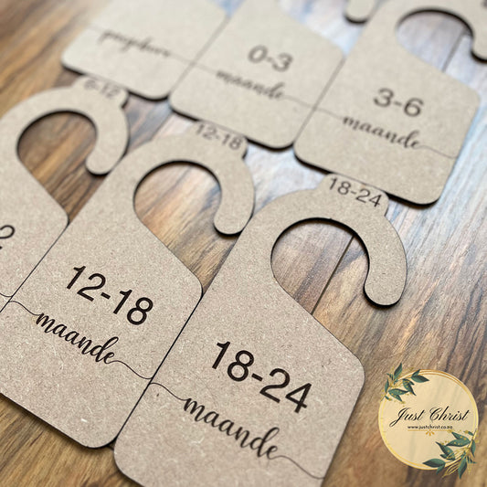 A close-up image of MDF wood closet dividers which is placed on laminated wood flooring for the image. Month categories are engraved on the closet dividers, eg. 12-18 months, 18-24 months.