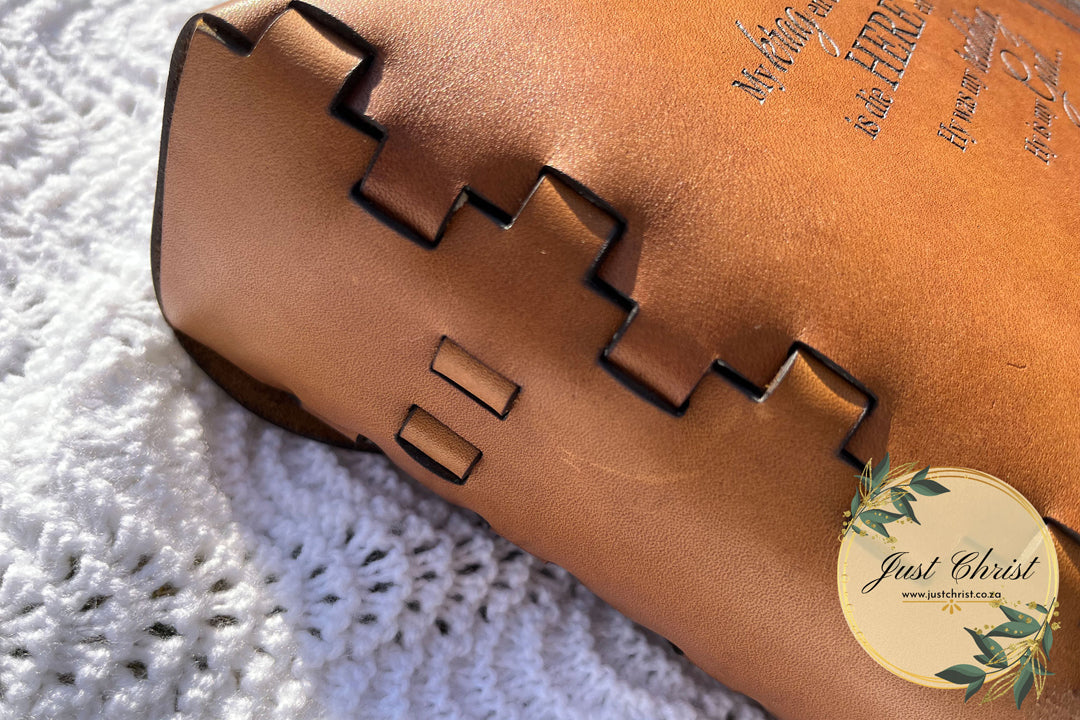 A close up image of a leather bible cover, the close-up shows the lace effect of the cover. In the upper right corner a short part of the engraved verse shows.