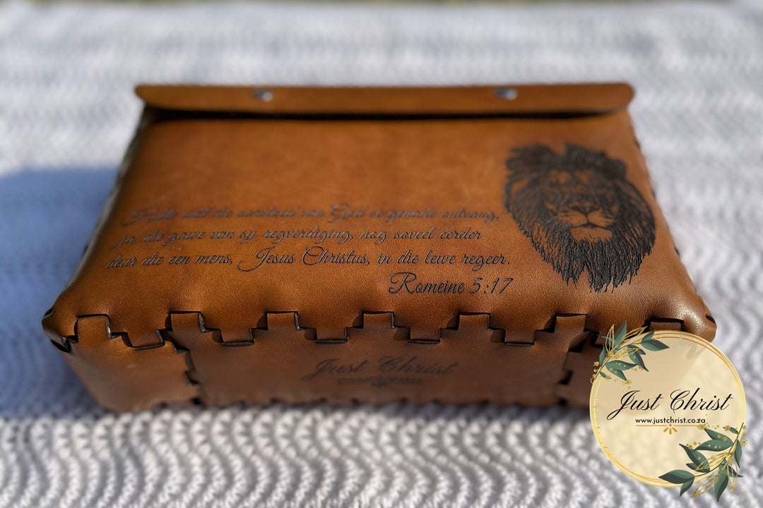 A beige Bible Cover boasting the lace effect, the Bible cover is on a white blanket, and a cat with a verse is engraved on the front. The image is taken from the bottom of the cover.