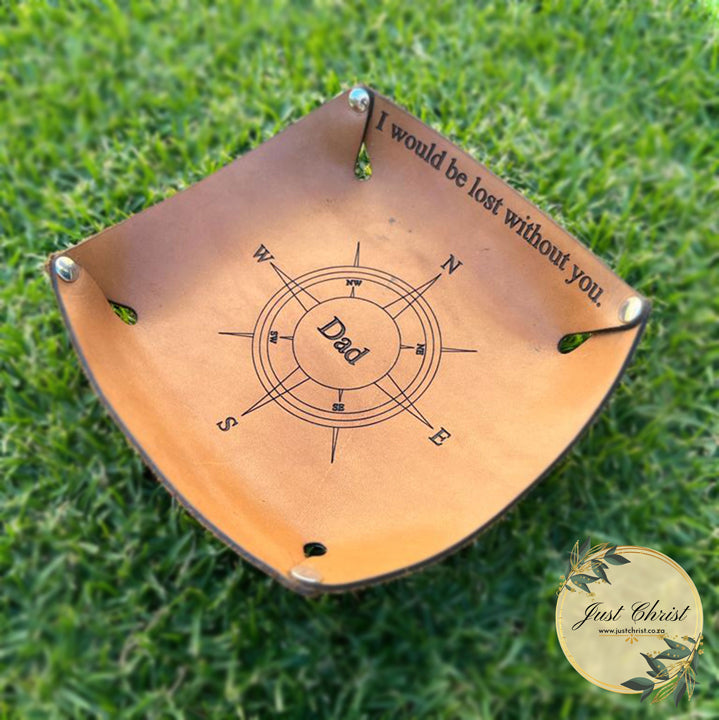 A square valet tray placed on grass. A compass with "dad" in the centre is engraved in the middle and "I would be lost without you." is engraved on one of the sides of the valet tray.