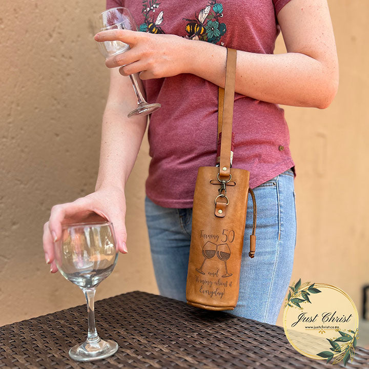 An action photo where a person is putting wine glasses on a table with a wine carrier on their arm. 