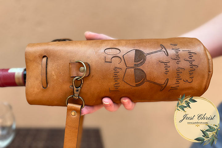 A close-up image of the engraving on the wine carrier, "Turning 50 and wining about it everyday!" with two glasses toasting.